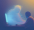A person sitting at night in front of a glowing screen, while an abstract human form seems to emerge in pixels and bluish mist.