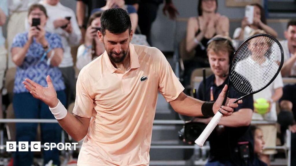 Novak Djokovic, wearing a peach polo shirt, dances with his racquet in his left hand