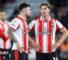 Two Southampton players, wearing red and white striped shirts and black shorts, in conversation