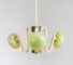 A modern chandelier by Sara Schoenberger, featuring three spherical green glass shades and gold metal arms, suspended against a plain light gray background.