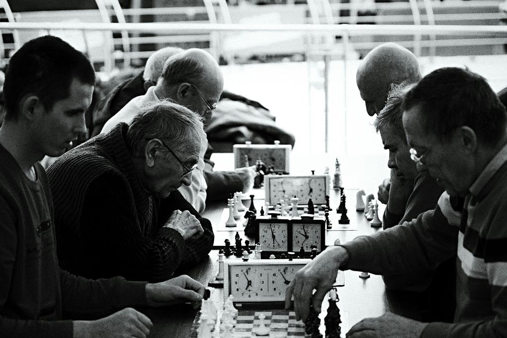 Black and white photograph of seven men playing chess